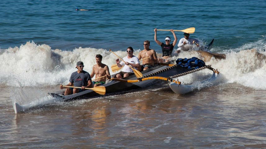 Outrigger canoe surfing in to the beach.