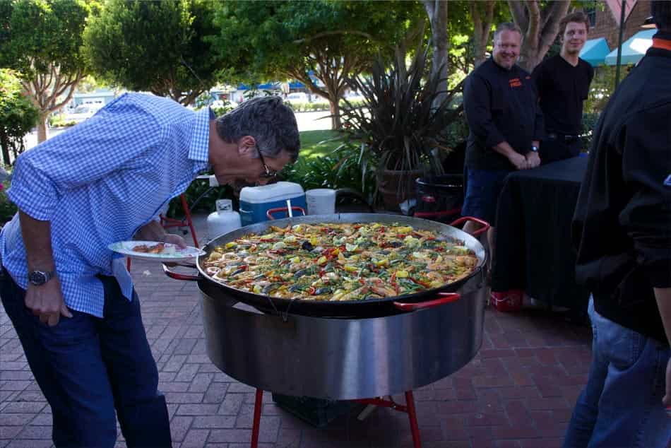 Digital Foundry team member leaning over to smell a large pan of paella.