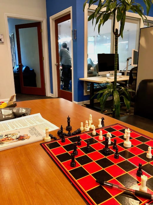 Red and black chess board set up on a wooden table.