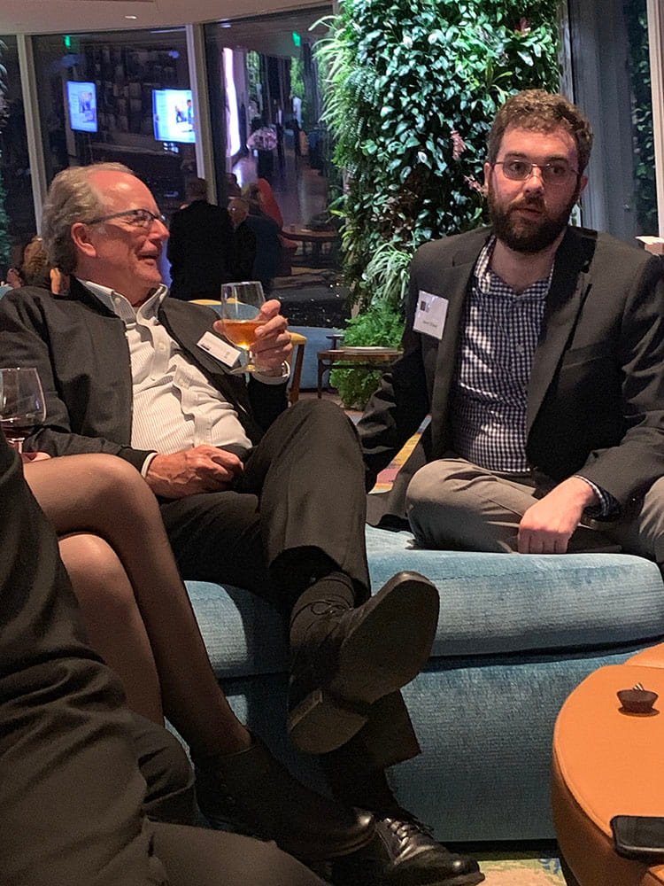 Two employees on a couch at a semi-formal gathering.