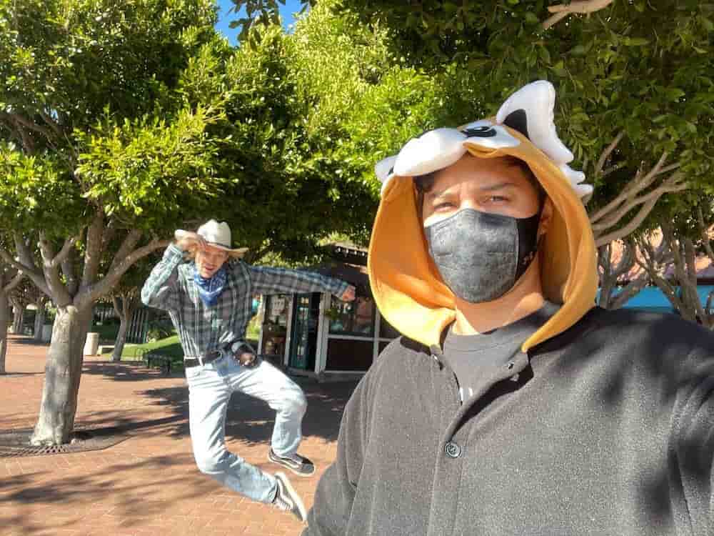 Halloween selfie in front of a man kicking up his heels in a cowboy costume.