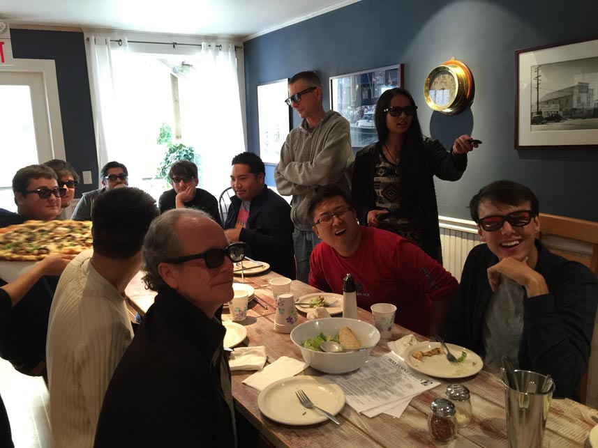 Group eating pizza and watching a movie wearing 3-D glasses.
