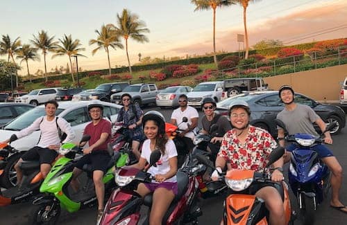 Eight employees going for a scooter ride at Maui offsite.