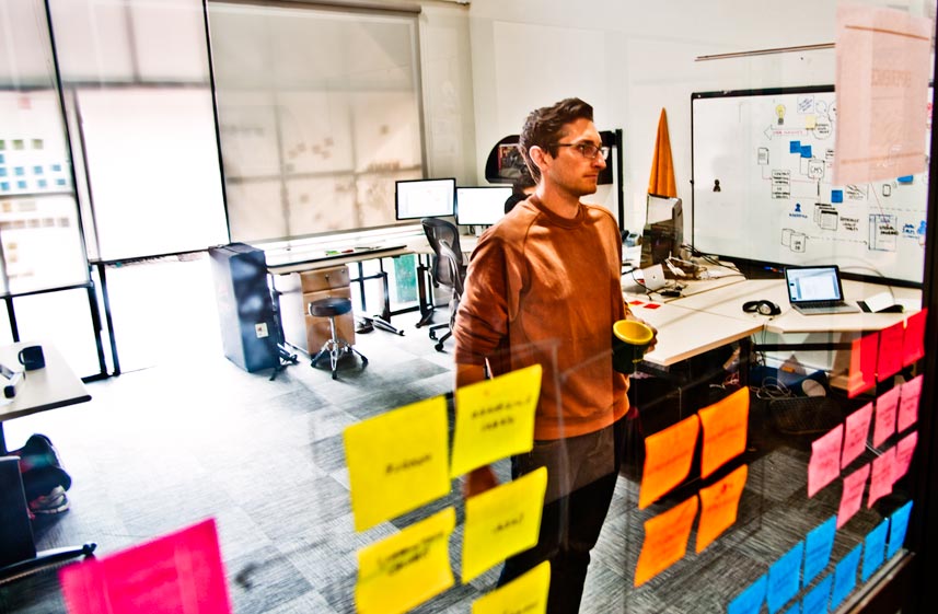 Software consultant categorizing requirements with color-coded sticky notes.