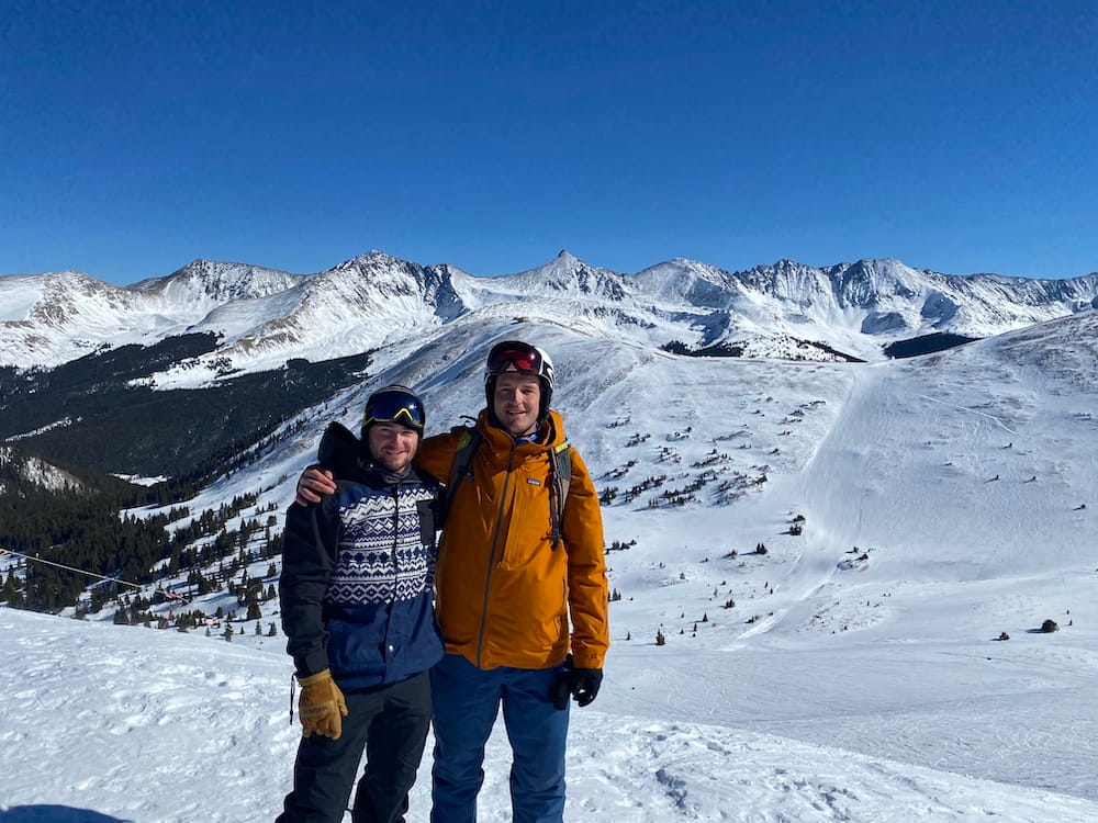 Two skiers posing in front of a mountain range in Colorado.